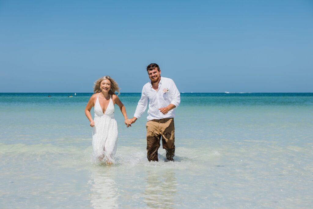 a bride and groom standing in the water in their wedding clothes after a beach elopement in florida, beach wedding, beach wedding planner