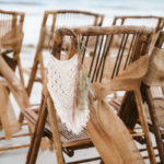 Bamboo chairs wrapped with burlap sashes. Hanging boho inspired macramé chair hangers with pompous grass aligning the wedding aisle.