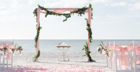 Whimsical garland wrapped around a 2 post white washed arbor with a blush petal aisle.